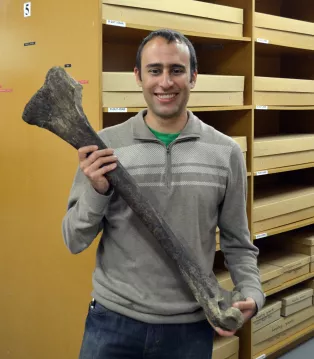 Photo of scientist Stephen Brusatte holding a fossilized bone.